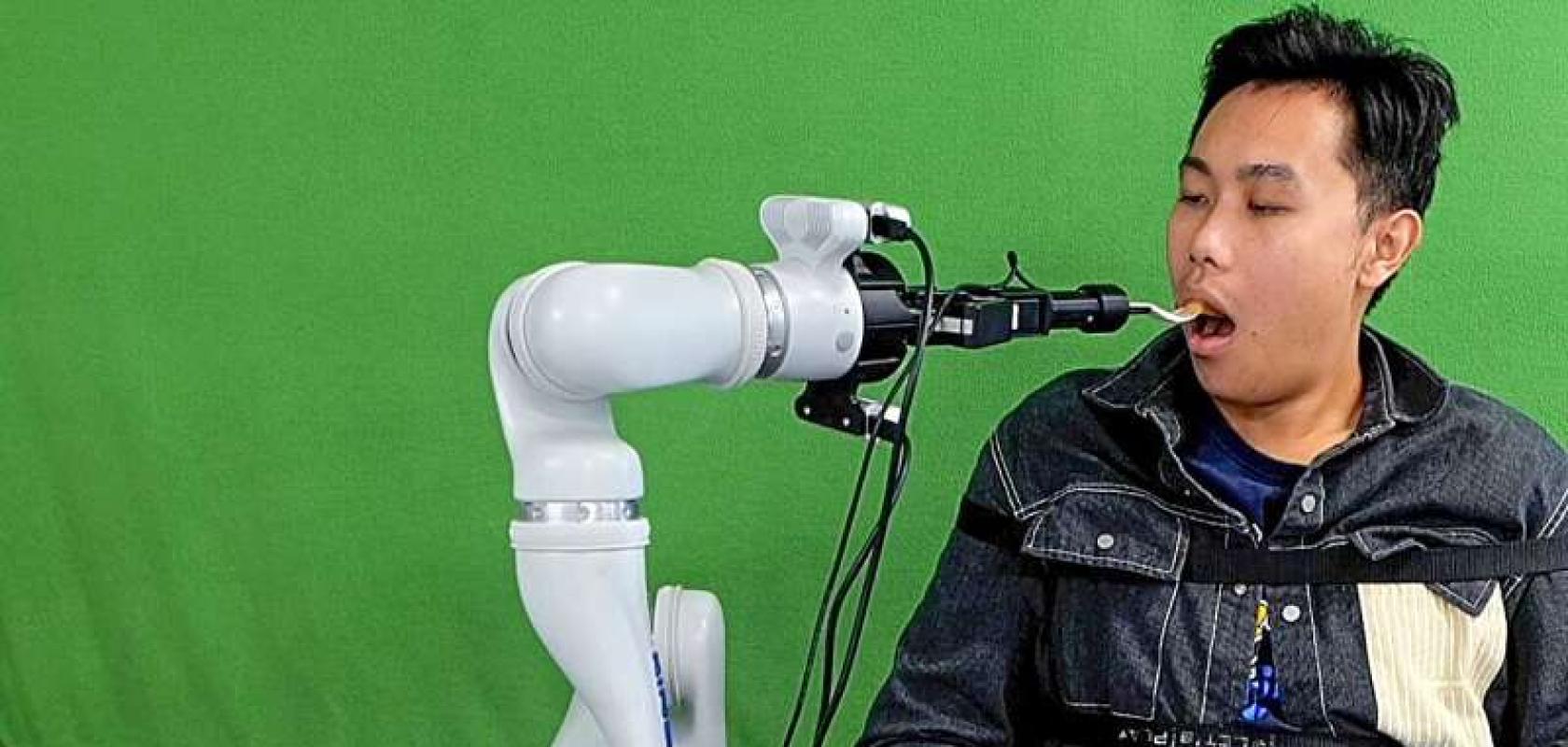 A robotic system developed by Cornell researchers feeds a student participant during a lab demonstration